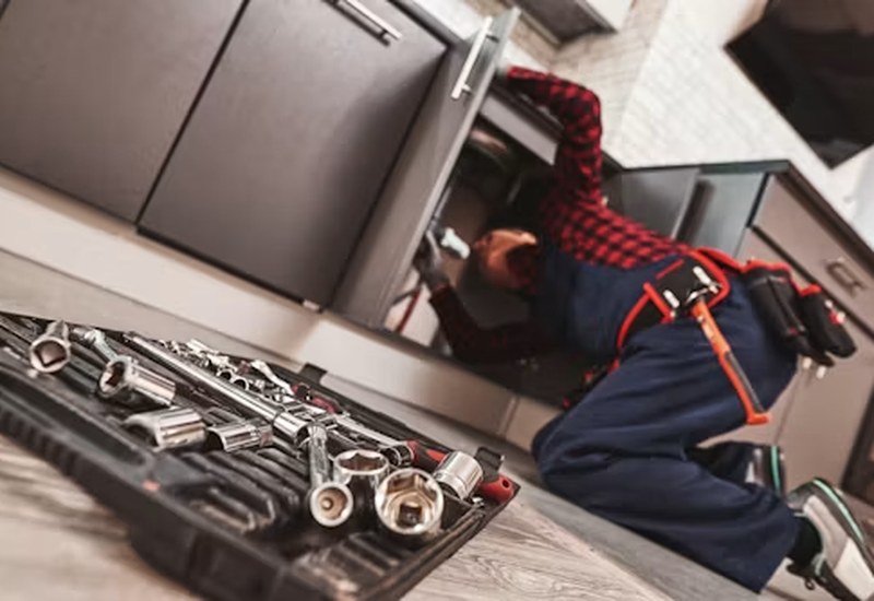 Plumber repairing a kitchen sink pipe in Abuja